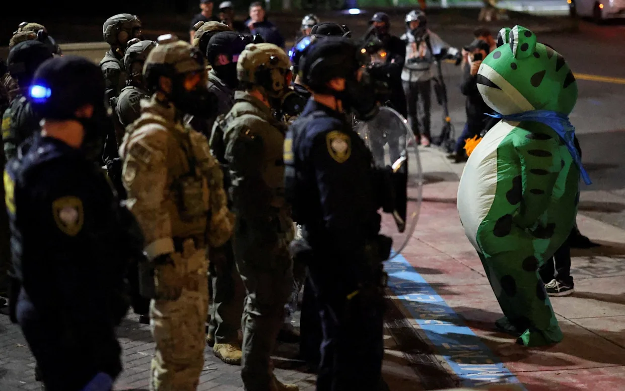 Seth Todd confronting immigration officers while wearing an inflatable frog costume